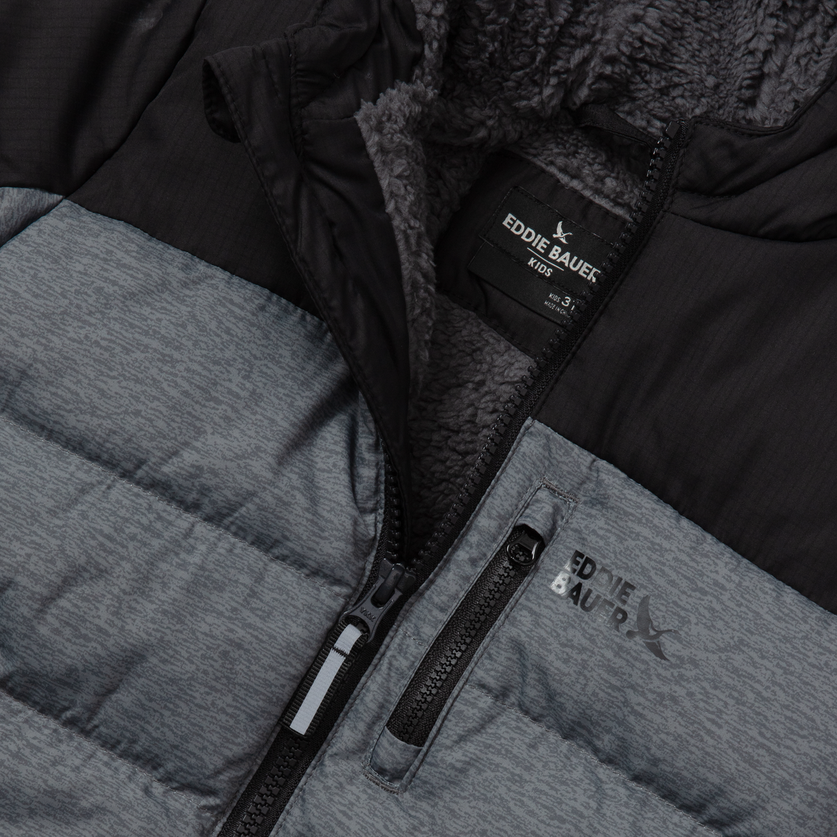 Black and gray quilted down jacket with textured fleece lining and front zippers, showing Eddie Bauer brand label.