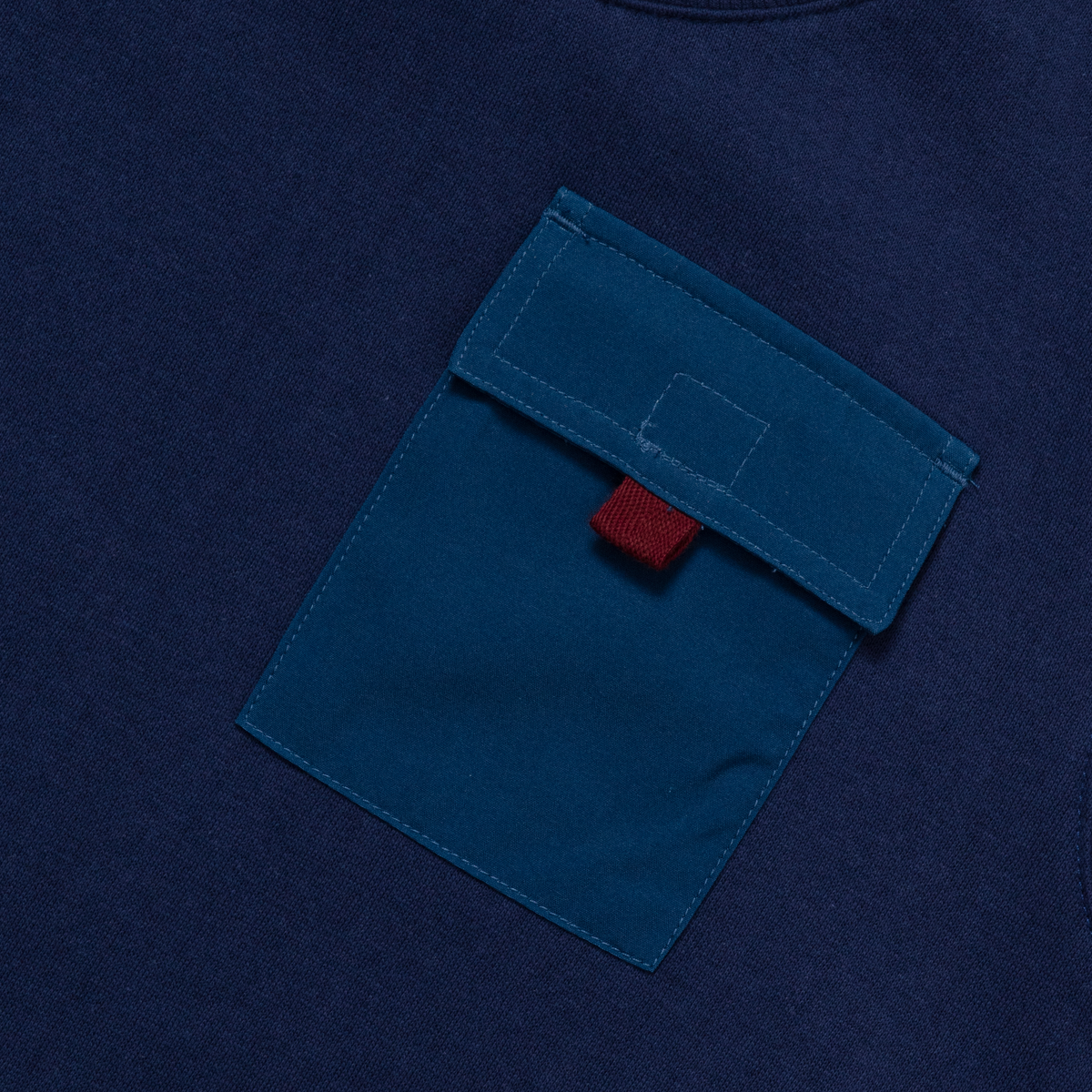 Navy fleece crewneck with teal front pocket and red label detail.