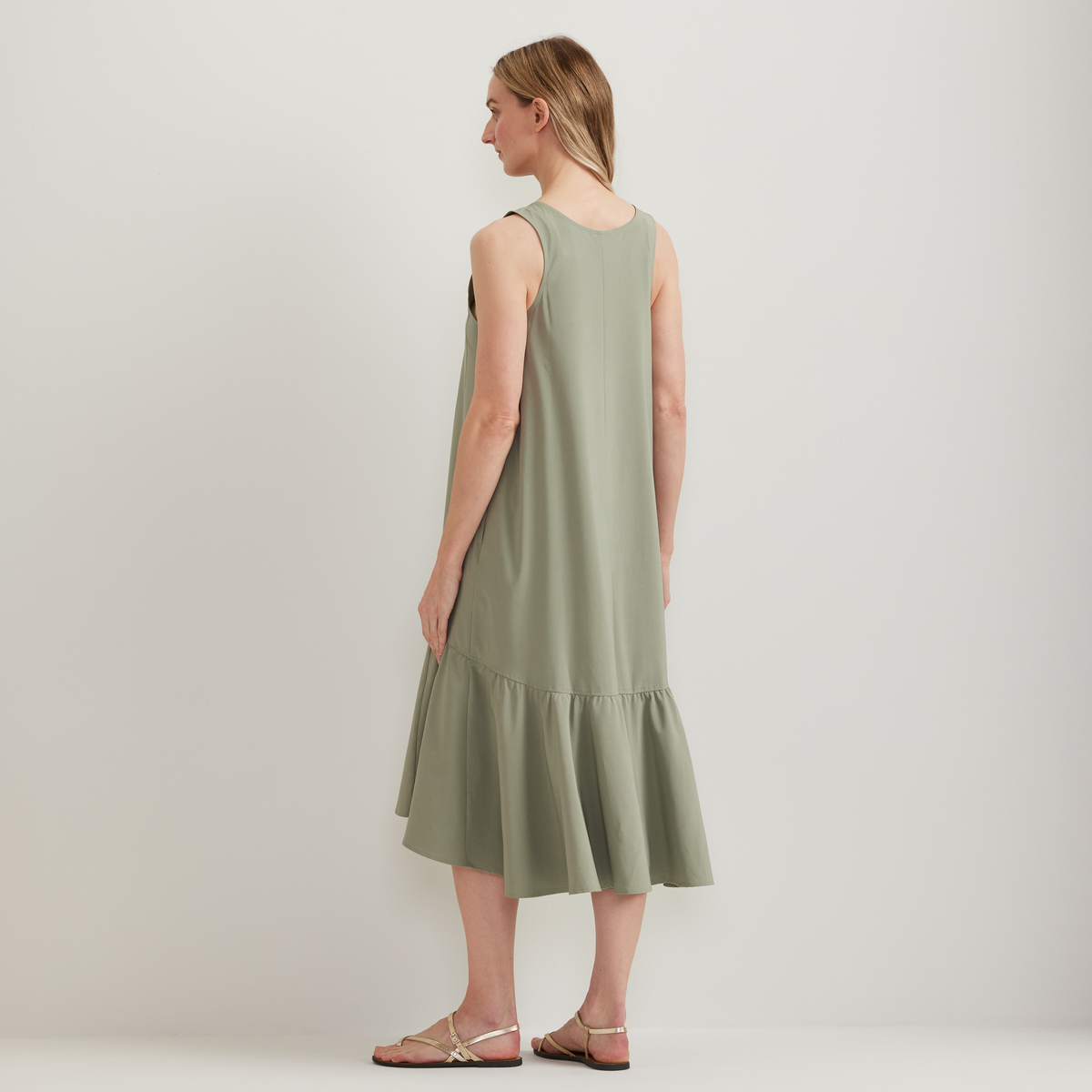 Sleeveless sage green midi dress with tiered ruffle hem, shown on model from back.