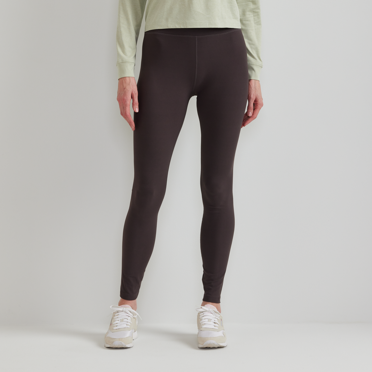 Black high-rise leggings with center seam detail, shown on model wearing white sneakers.