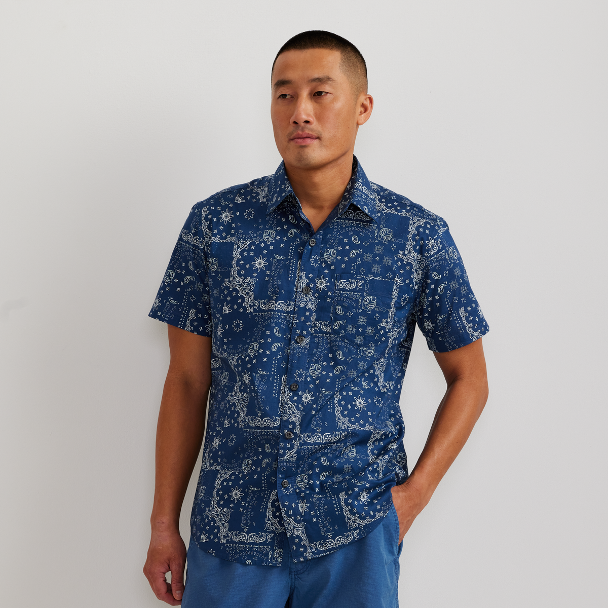 Navy short-sleeve button-up shirt with white geometric and floral print pattern.
