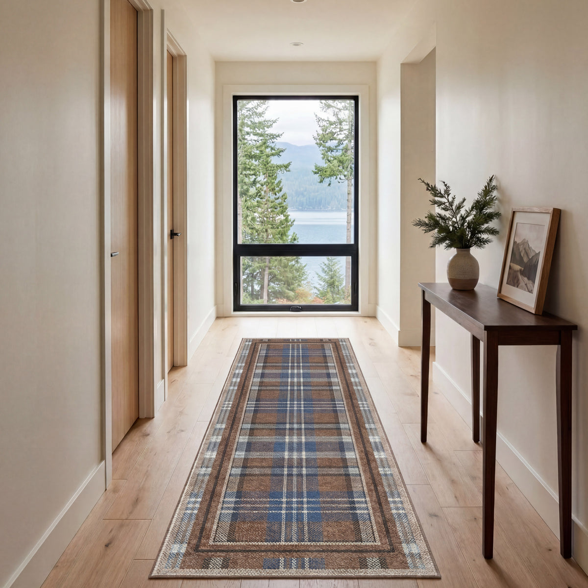 Hallway with a plaid runner rug, wooden floor, and a view of trees and water through a window.