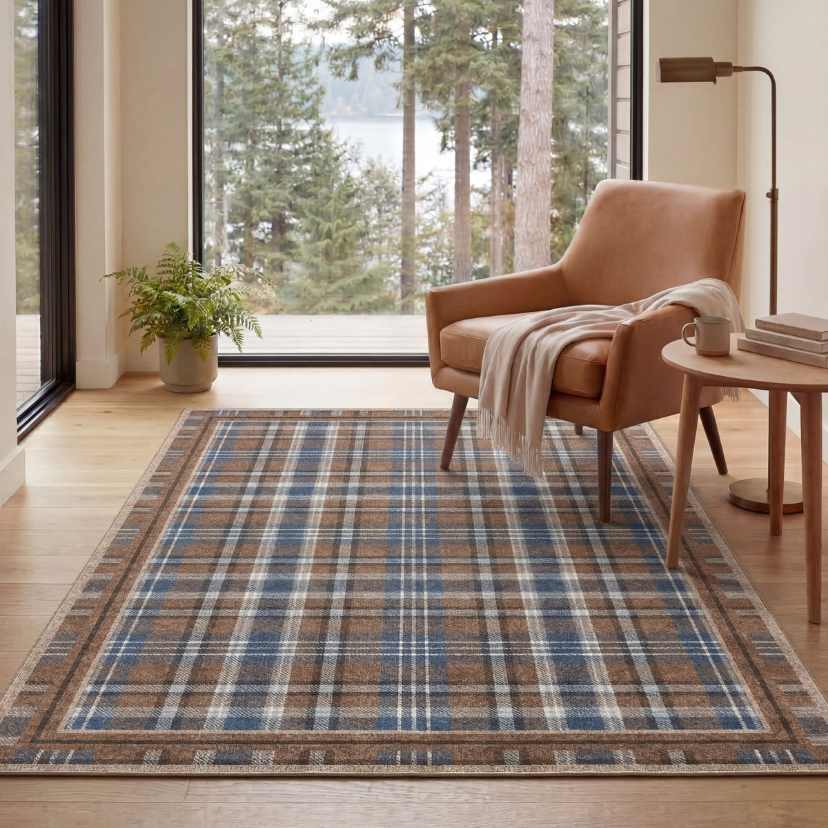 Living room with a plaid rug, brown armchair, and large windows overlooking trees.
