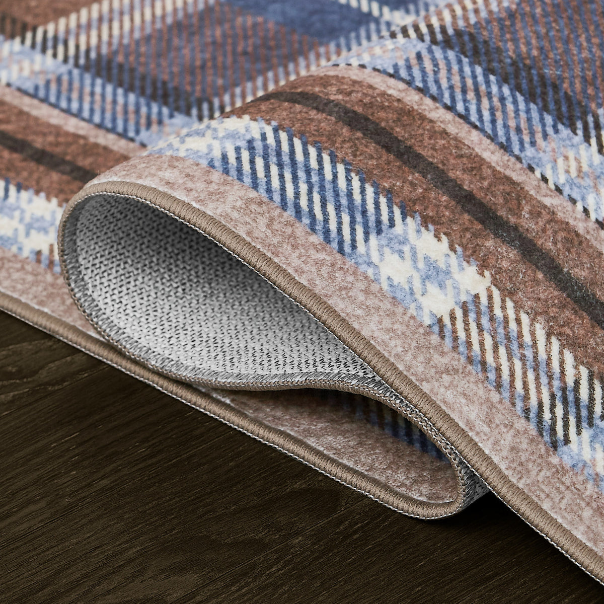 Patterned rug with brown, blue, and beige colors on a wooden floor.