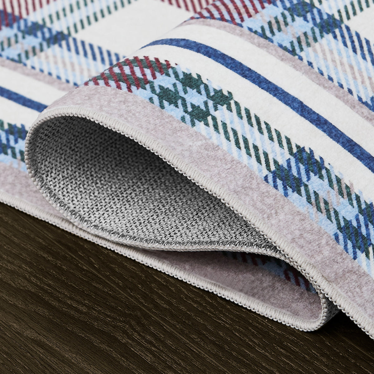 Close-up of a textured rug with plaid pattern on a wooden floor.