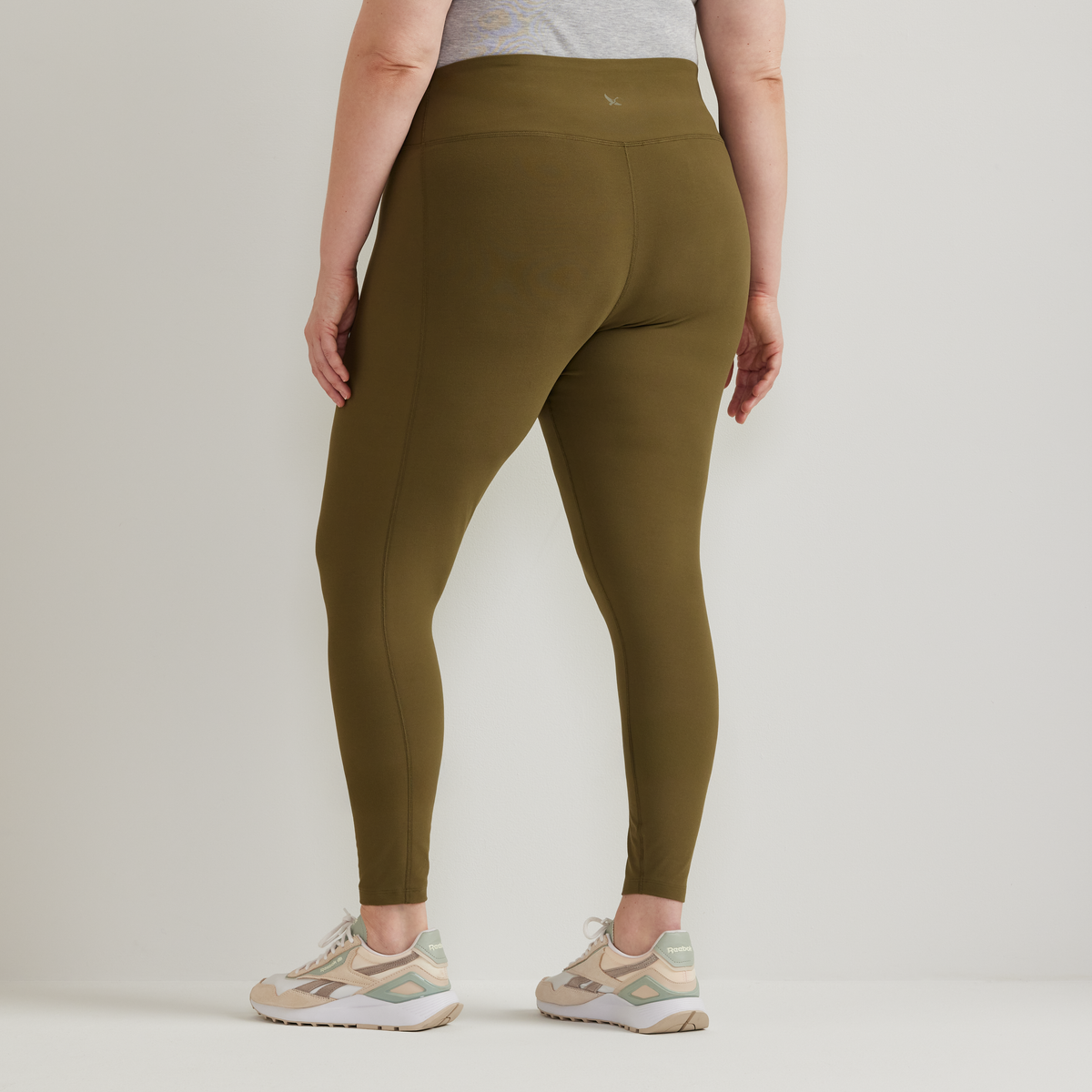 Olive high-rise leggings with side seam detail, shown from behind on model wearing gray top and beige sneakers.