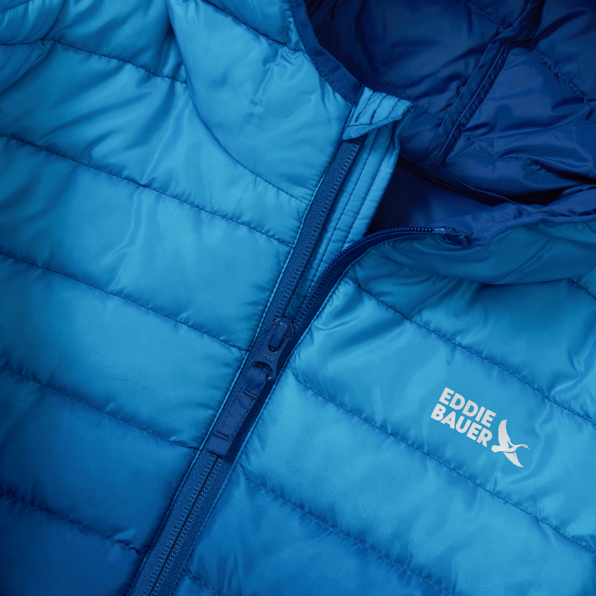 Blue quilted down jacket with full-length zip and Eddie Bauer logo visible on chest.