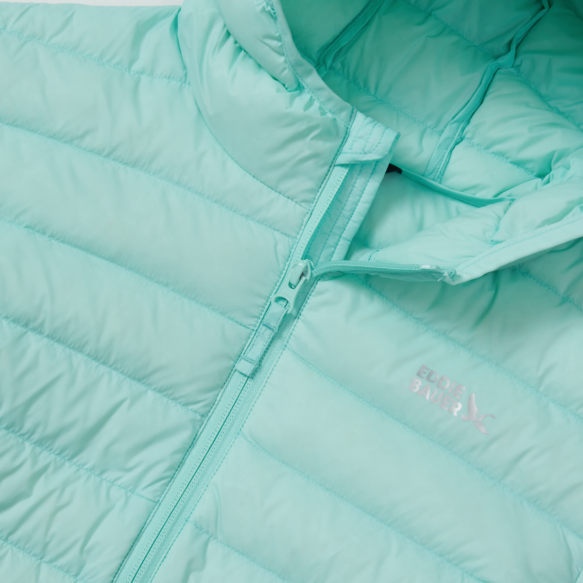 Light blue quilted down jacket with full-length zipper, hood detail, and diagonal stitching pattern visible.