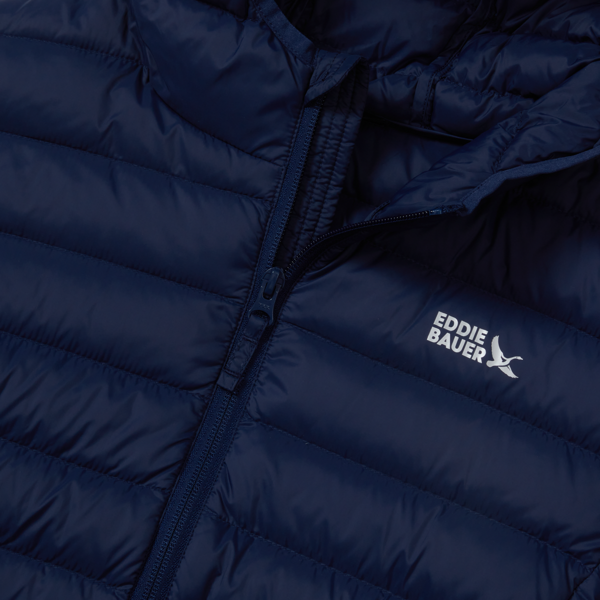 Navy blue quilted down jacket with full-length zipper and Eddie Bauer branding on chest.